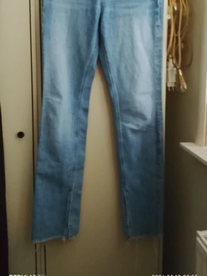 Ljusblå raka jeans med råa benslut - Ljusblå jeans i rak modell med klassisk femficksdesign och råa, avklippta benslut. Jeansen är tillverkade i denim och har en enkel, stilren look utan synligt märke. Perfekta för en avslappnad och trendig stil.