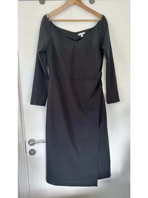 H&M svart klänning med bara axlar - storlek 44 - Stilren svart klänning / cocktailklänning med bara axlar från H&M i storlek 44. Tidlös modell med långa ärmar och en elegant omlottdesign. Klänningen har en smickrande V-ringning framtill och en rakare skärning baktill. Detaljer som diskreta rynkningar i sidan bidrar till en fin passform. Klänningen är knälång och passar för olika tillfällen. Diskret dragkedja i sidan. Mycket fint skick, som ny!