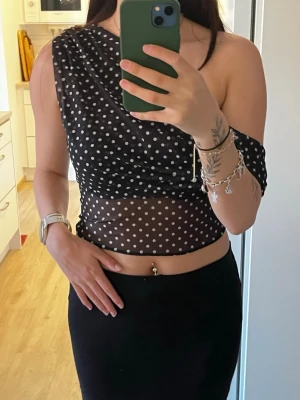 Svart prickig oneshoulder topp - Trendig svart mesh-topp med vita prickar och oneshoulder-design. Helt oanvänd🫶🏼