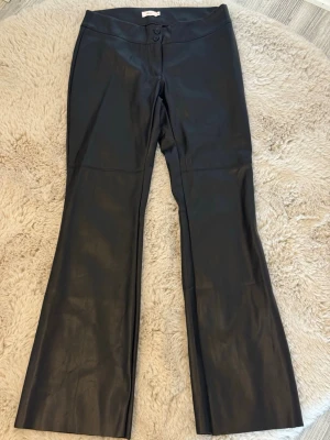 Svarta utsvängda low waist läderbyxor från Nelly  - Säljer mina as snygga lowwaist  läderbyxor från Nelly! Använda 1-2 gånger, inga tecken på användnings alls! Storlek 38!💕