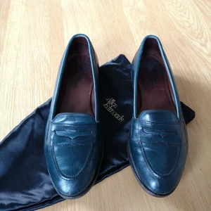 Loafers Allen Edmonds storlek 39 - Superfina loafers från Allen Edmonds. Storlek 39. Äkta läder med mörkgrön/turkos nyans. Har några repor och en liten skada i lädret längst fram på högerskon men i övrigt mycket bra skick. Kommer i tillhörande förvaringspåsar i siden. 
