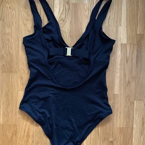 Baddräkt - Baddräkt i svart från Lindex, storlek 38. Högt skurna höfter och spänne i ryggen. Använd ett fåtal gånger.