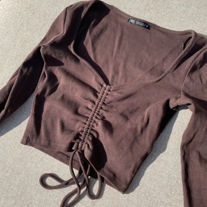 Zara brun topp med knytning  - Säljer denna populära, slutsålda toppen från zara! Superskönt material i trendig brun färg. Säljer den då jag köpte fel storlek så den är använd endast en gång