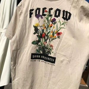 T-Shirt med blommigt tryck - En fett skön t-shirt i tunnt material. Snygg beige färg med stort blommigt tryck på ryggen.                       Cond: 8/10                                                                           Storlek: L men sitter perfekt som en lite oversize M