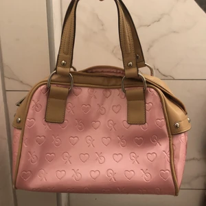 Babyrosa vintage handväska  - Jättegullig babyrosa och y2k/2000s aktig väska med beige handtag samt silvriga detaljer! Från min mamma själv och användits under ett tag. Skicka ifall ni vill ha fler bilder då det finns lite mer defekter. Den är 30 x 20 cm. Men väldigt unik i helhet då den inte finns på marknaden.