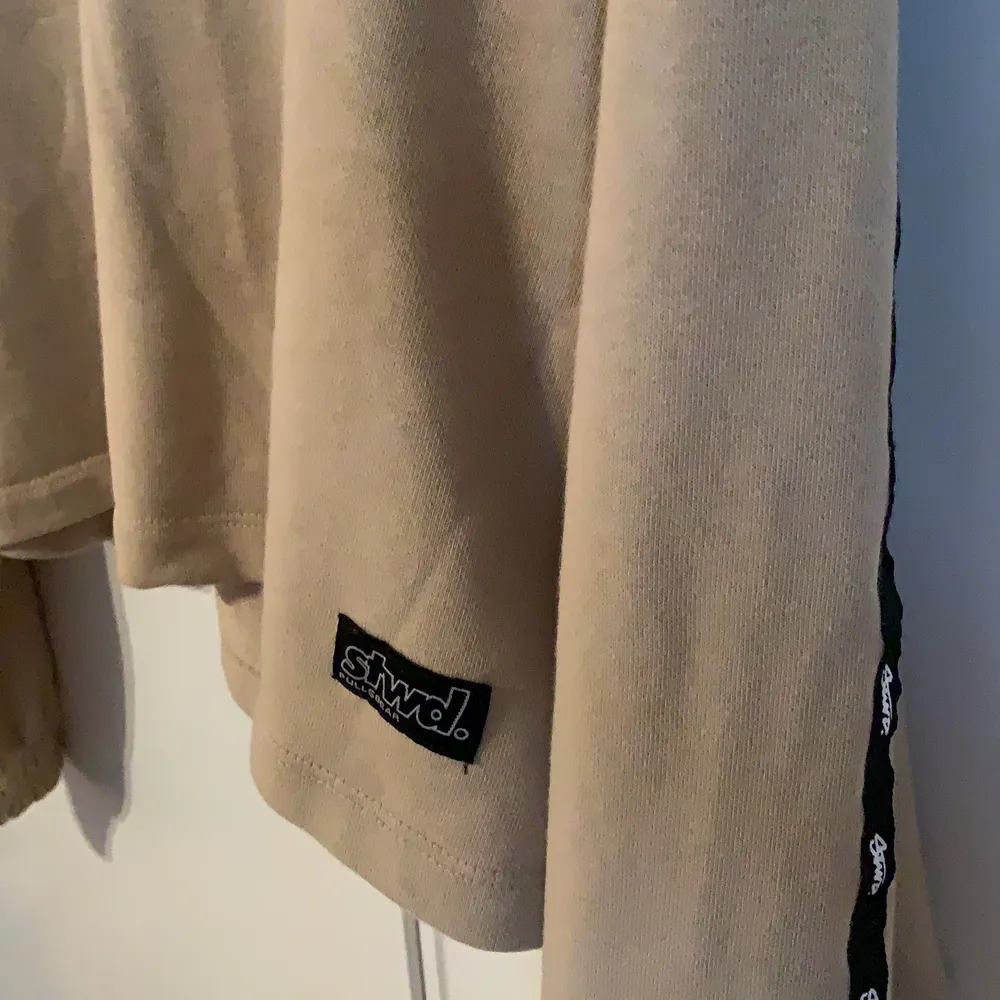 Beige sweatshirt från pull&bear med coola detaljer på ärmarna:) Storlek m men rätt kort så passar även s. Tröjor & Koftor.