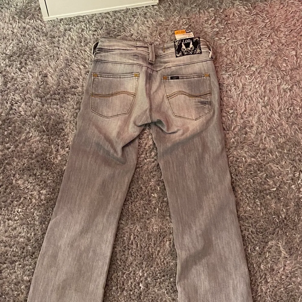 Grå bootcut jeans från Lee. Modellen är Cade Patch och har ett väldigt fint märke på baksidan med silver detaljer. Byxorna är i bra skick, nästan aldrig använda. Storlek W24 L31 ungefär XS. Modellen på bilden är 1,66 m. Jeans & Byxor.