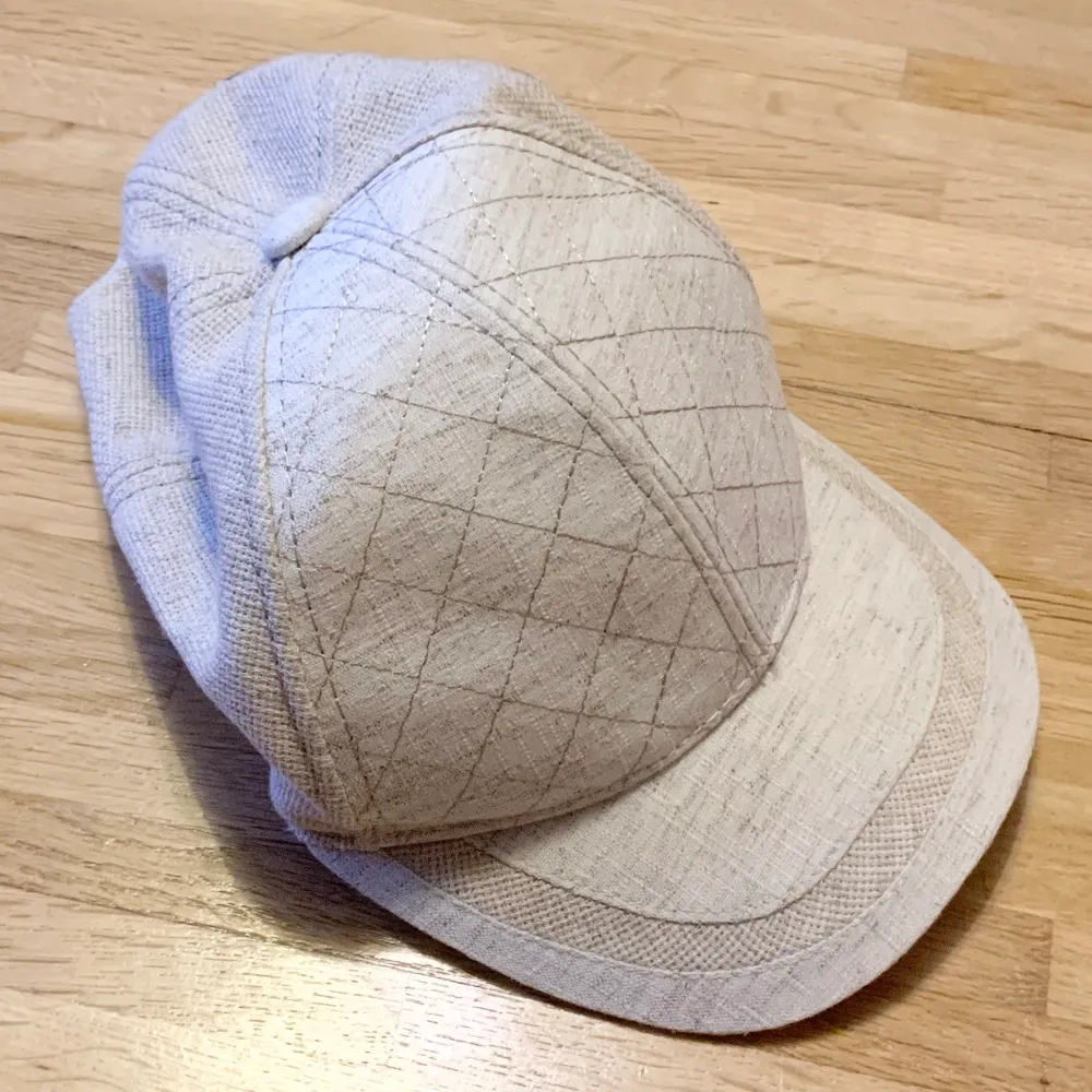 Ljusbeige keps. Styvare i pannan än övriga kepsen. Reglerbar i bakhuvudet. Accessoarer.