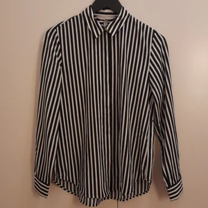 Svart/vit randig skjorta strl 34 - Svart/vit randig skjorta från H&M. 100% Polyester. Strl 34. Ej använd.