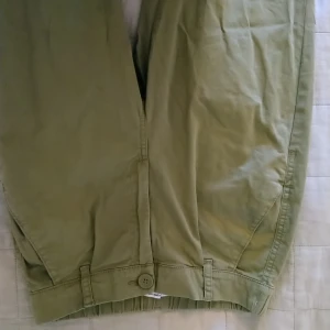 Byxor stl36 - Cargo inspirerande byxor i väldigt mjukt tyg, med resår i beslutet. Fuskfickor på rumpan och sneda fickor fram. Gylf och knapp. Storlek 36, använda endast ett par gånger. 