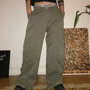 Cargobyxor - Asfeta gröna lowwaisted cargobyxor! Man kan justera storleken i midjan. Midjemått 80 cm, innerbenslängd 75 cm, midja till gren 24 cm. Långa på mig som är 164 cm :)