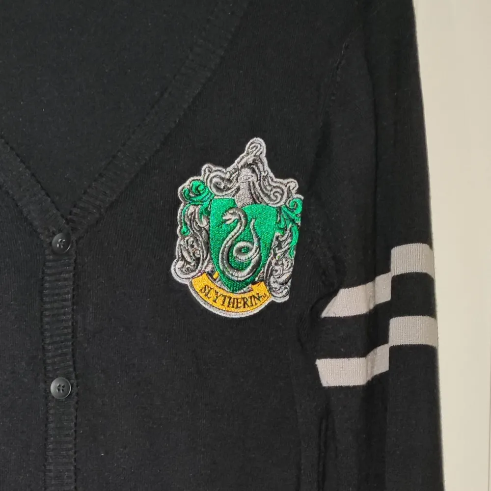 Oanvänd official Harry Potter kofta med Slytherins märke och färger. . Tröjor & Koftor.