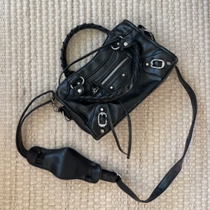 Väska i strl S - Väska i strl S som är identisk med Balenciagas väska. Perfekt att ha över axeln eller som axelremsväska. Väskan är knappt använd och är därför i gott skick! Priset går att diskutera, buda🤩 högsta bud ligger på 770kr!!!