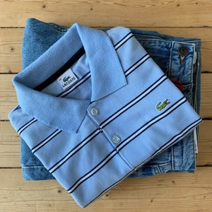 Pikétröja från Lacoste, strl S - En randig ljusblå pikétröja från Lacoste. Skick: 9/10. Storlek: M herr men passar som S 