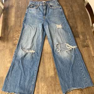 mörkblå utsvängda jeans med hål från gina tricot, väl använda och i bra skick!