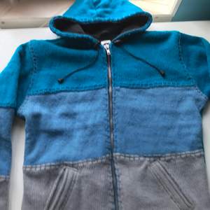 Stickad hoodie med olika nyanser av blå. Coola sömmar. Helt oanvänd och perfekt för hösten.                    Orginalpris: 400kr