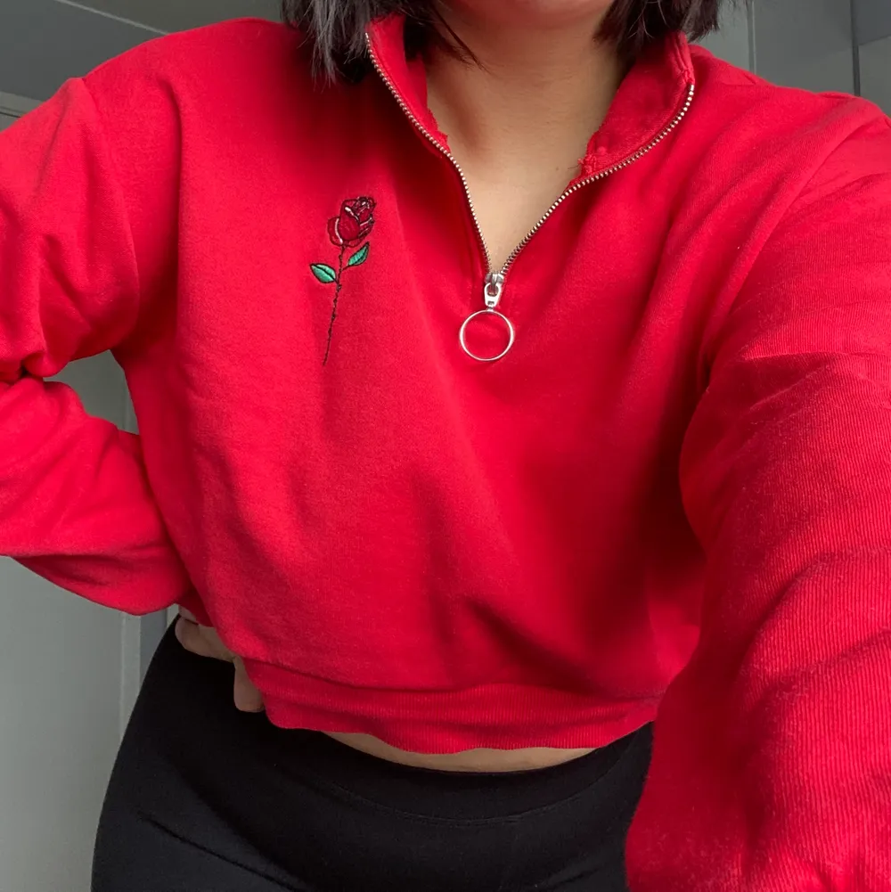 Röd tröja från H&M med dragkedja och rosmotiv. Kort passform. Hyfsat bra skick. Jag bär vanligtvis storlek M/L på toppar/tröjor och är 172 cm lång.. Tröjor & Koftor.