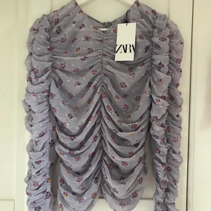 Glittrig topp med blommor  - Har aldrig använt toppen. Den är lite genomskinlig och sitter jättefint på kroppen. 