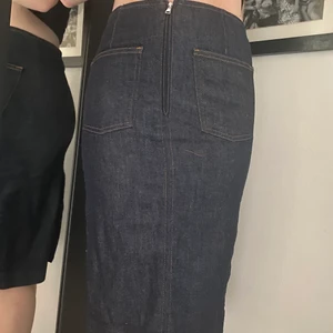 Filippa K jeanskjol - Snygg och unik jeanskjol från Filippa K. Knälång, mörkblå i 70-tals stil med 2 fickor och en liten slits på baksidan. Passar storlek S. 