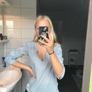 Jättefin ljusblå blus! - Jättegullig ljusblå blus med massa fina mönster och brodyr. Den är ganska genomskinlig, så jag rekommenderar att ha ett linne under, men funkar även utan som på bilden. Helt nyskick. Storlek 1 = storlek S. Säljer pga att den sällan kommer till användning. Köparen står för frakten och jag vet att den är dyr, därför är priset på plagget sänkt!