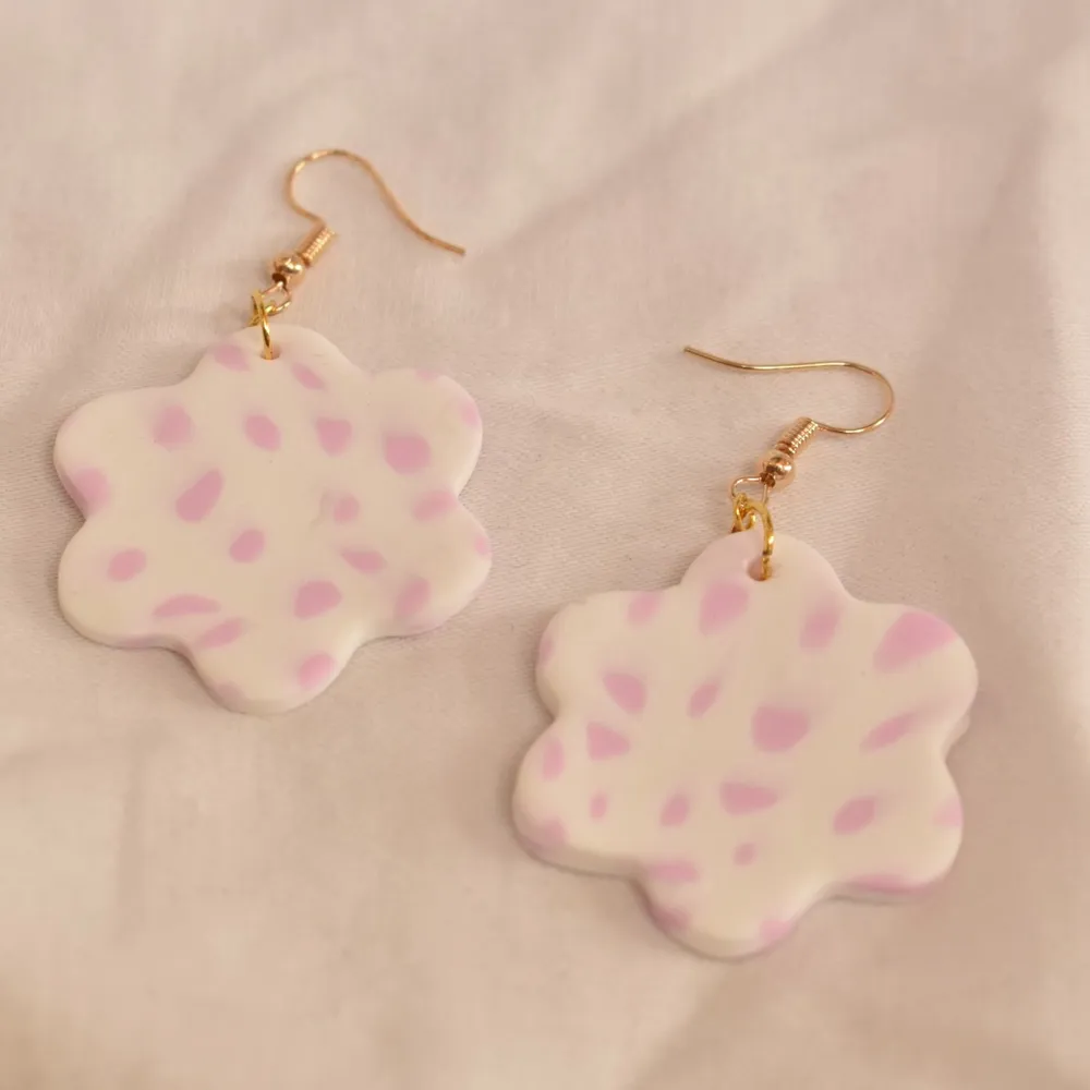 Blomform, vit bakgrund med rosa mönster. Handgjorda örhängen utav polymer lera med guldhänge, ca 3-4 cm i diamanter. 79kr + 20kr frakt . Asusteet.