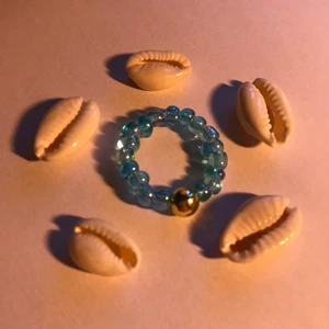 Blå Ring! - Ring med små blå genomskinliga pärlor, en rund guld pärla och elastisk tråd! Runt 6 cm! 15kr plus frakt!