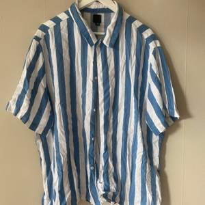 En skjorta ifrån HM som är i ganska stor pass form. Skjortan har breda ränder i blå och vit med längre ärmar  