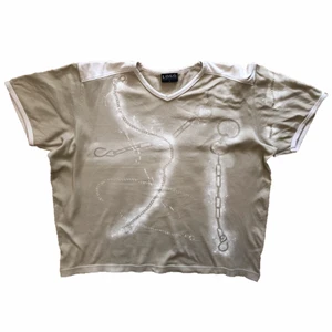 beige oversize tshirt  - en v-ringad tshirt som är omgjord med textilfärg som avbildar kedjor i olika former! plaggets längd är ca 61 cm, skriv om du vill ha fler bilder eller mått 🤍 