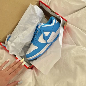 Nike Dunk Low UNC - Nike Dunk Low UNC 💙 Ingen budgivning utan den första som är redo att betala får dem! Använda 4 gånger så fint skick. Originalkartongen är lite skadad men inget som påverkar skorna såklart. I nyskick är lägsta begärda pris $378 för dessa på stockx! 😊