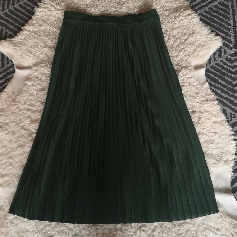 Grön plisserad kjol med fin passform och fall. Dragkedja och knappar på sidan. Fint skick! . Kjolar.