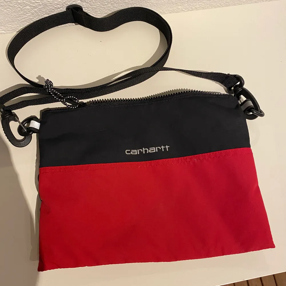 Hej! Säljer en carhartt dexter strap bag i färgen röd och svart, väskan har aldrig kommit till använding så den är som ny. Om du har någon frågar så är det bara att fråga på:) . Väskor.