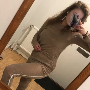 Glittrigt nude set  - Glittrig nude dress med en vit rand på sidan, beställd från Nelly. Passar bra till både hemmakvällar & fest 🍿💃🏻  Storlek S, men passar även M (stretchmaterial). Byxorna har en bekväm resår i midjan och fickor framtill. Nyskick! Sparsamt använt, inga skavanker💫