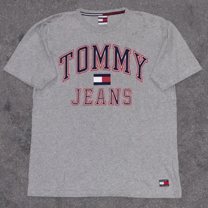 Tommy Jeans 90’s Capsule Logo T-Shirt - Grå t-shirt med Tommy Hilfiger tryck. Skick 8/10 och sitter som en M-L, lite oversize modell.🌟 Snygg och längre ärmar.