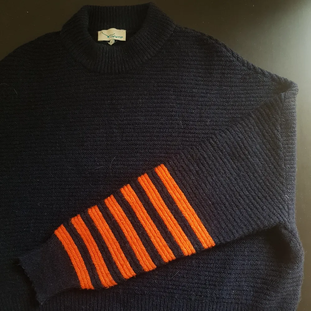 Fin stickad tröja i mörk marinblå med orangea detaljer. Inte använt alls och är i fin skick. . Stickat.