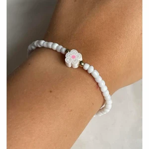 White flower  - Vit armband med lite guldiga detaljer med en vit blomma i mitten 🤍 ingår spänne och ringödlor så man kan justera det efter önskan 🤍 man väljer även vilken storlek man vill ha det i.
