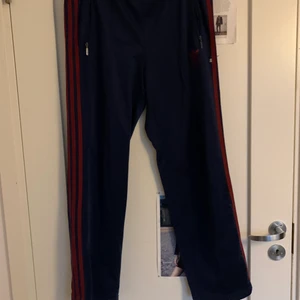 Adidasbyxor  - Adidasbyxor, mörkblå och röda ränder på sidan.