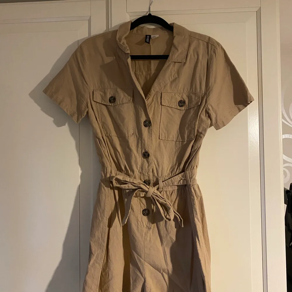 Beige jumpsuit i nyskick. Lite skrynklig på bilden då den legat nedpackad. . Övrigt.