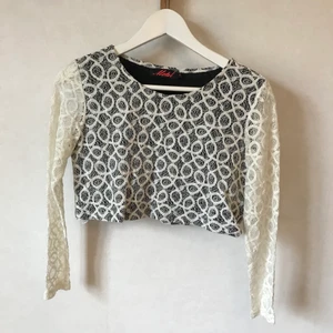Långärmad croptop i spets, XS-S - Helt underbar långärmad magtröja i vitt virkat mönster eller spets på! Har en svart insida så den inte blir genomskinlig över brösten. Helt nyskick! 67% bomull. Uppskattar till XS eller S.  Kan mötas i Stockholm eller skicka mot fraktkostnad! ✨🌸✨