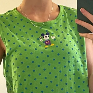 Grön mickey mouse sleevless t-shirt  - En grön arm-lös tröja med blå prickar. Cool icon på framsidan av Musse pigg. Cool att styla. Kommer från en Disney Store men jag köpte den second hand i Lund. 