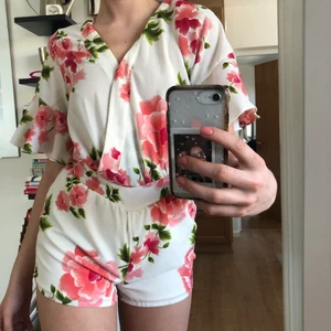 Vit byxdress med rosa blommor - Väldigt fin byxdress. Fin passform och ärmar, wrap vid bysten. Säljes pga för liten.