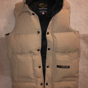 Canada Goose Väst Strl. XXS-XS-S - Strl. XXS-XS-S passar perfekt. Snygg med alla kläder, praktisk i alla väder, äkta, lätt för alla tillfällen och alltid modern!  Passar både män och kvinnor. Man kan ha den under jackan vid kylan och ovanpå nån tröja bara hösten ut. Färgen är också festlig beige inte tråkig i höstmörkret. Den lyfter upp din hårfärg på ett fint sätt 😊