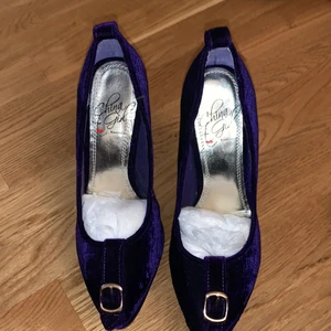 Klackar - Mörklila klackar med hög klack i velvet material från Nelly. Aldrig använda.