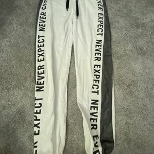 Byxor  - Ett par vita skor från NewYorker med svart text det står ”never expect”. 