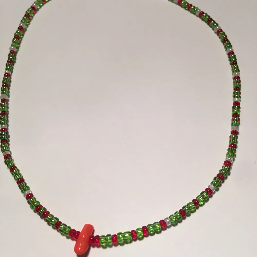 Handgjort halsband med glaspärlor i färgena vit, grön, röd och en större pärla i orange✨Kontakta om du är intresserad✨. Accessoarer.
