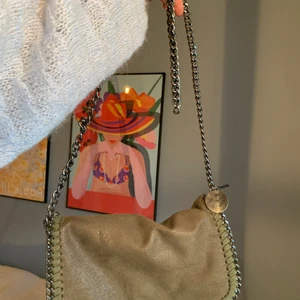 Handväska - En snygg väska i lagom storlek, väskan är i ett grönskimrande tyg (mockaimitation) med en mörkt silvrig kedja. Väskan har ett innerfack med dragkedja och två öppna småfack i väskan!   Köparen står för frakt!😃