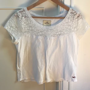 Hollister blus - En vit plus från Hollister strl M. Modellen är ganska kort och bred men i väldigt bra skick! Materialet är mjukt och t-shirt liknande nertill, medan det är spets och pärlor upptill.
