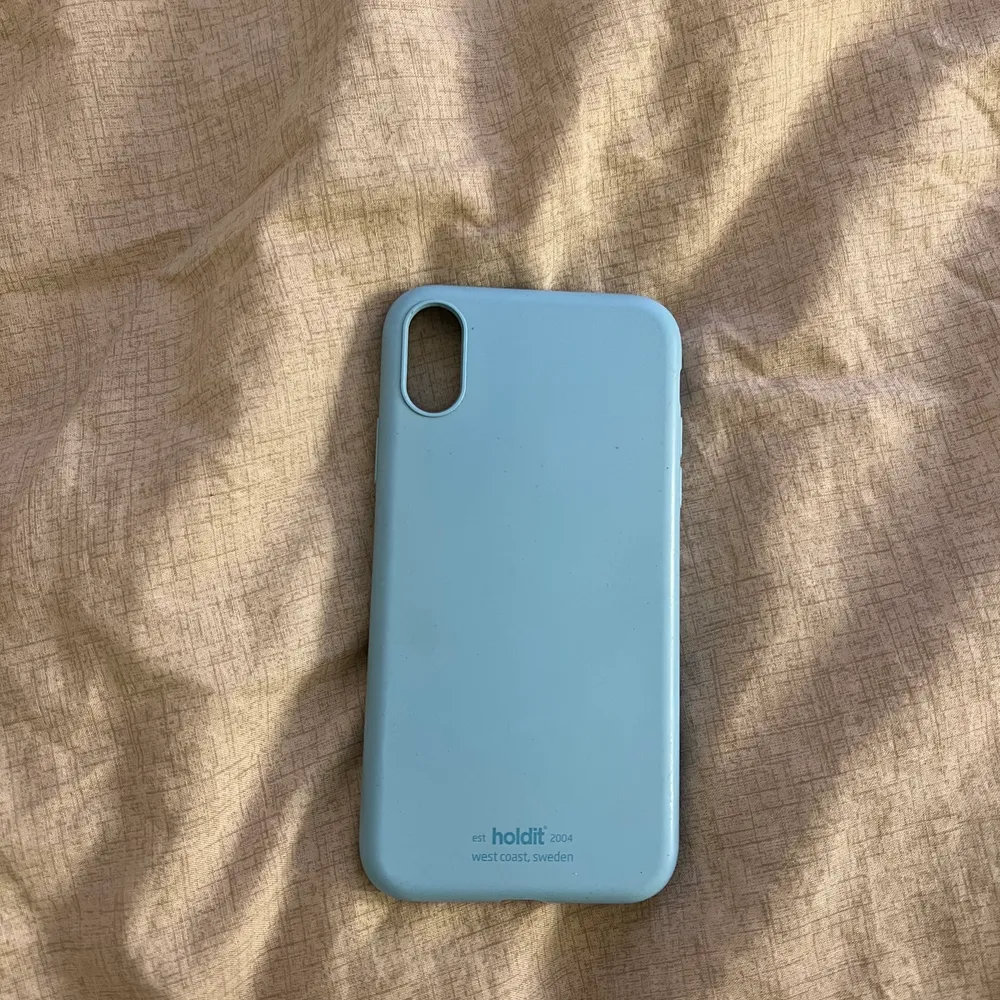 Ett mobilskal till IPhone XR från holdit i ljus blått. Lite trasigt i kanterna men det går fortfarande att använda.. Övrigt.