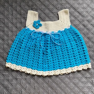 Virkad blå baby klänning - Denna baby klänning har jag virkat själv.  Den passar barn 3-6 månader Den är 40cm bred i kjolen och bröst mått är 24cm.   På baksidan finns en knapp Garnet är av bomull och tvättas i 30 grader.  Finns i rök och djurfritt hem