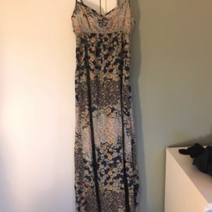 Långklänning med blommit tyg från H&M  - Klänningen har mjukt och tunt blommigt tyg men man ser inte igenom, jag är 1,65 och den går ner till fötterna. Tror den passar en A/B eller kaknske C kupa. Den är från H&M men jag köptes den på Sellpy för 100kr. Jag älskar klänningen men säljer för den jag inte tror jag kommer använda den och för den är lite för lång, men den går ju alltid att klippa av. Den är i fint skick och bass tonnen är mörkblå. För fler bilder hör av er. Kan tänkas starta en budgivning.💕       (Köparen står för frakten)