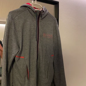 Hugo Boss hoodie - Grå Hugo boss hoodie med röda detaljer.